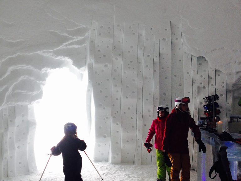 Un bambino con gli sci entra nel corridoio di un villaggio di igloo