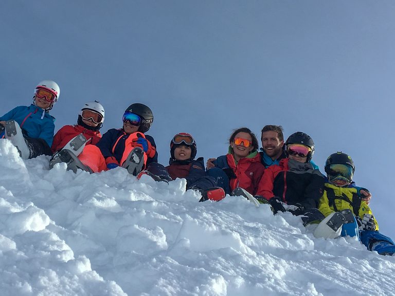 Un gruppo di bambini affacciato da un muretto di neve
